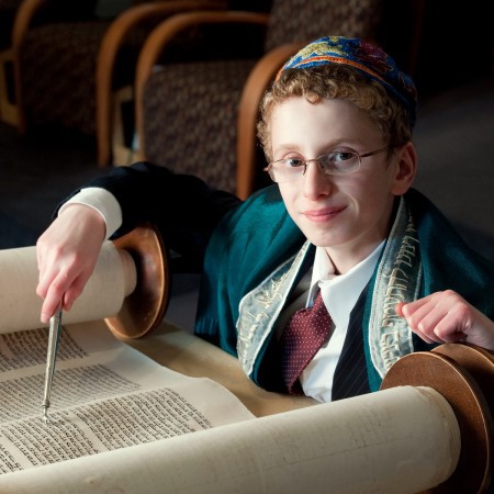 A bar mitzvah boy reading from a Torah scroll